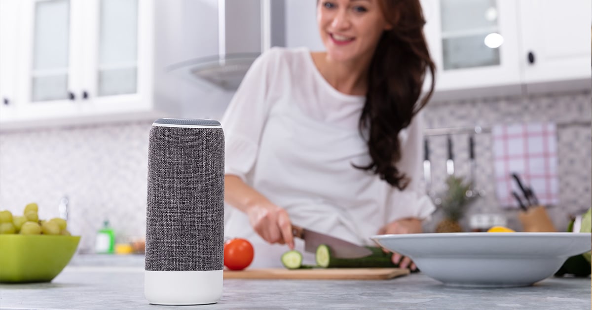 woman listening to local radio on smart speaker while she cooks in kitchen